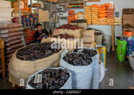Oaxaca, Mexiko - 2019-11-16-mann Anbieter Uhren sein Telefon im Laden gefüllt mit Chilis. Stockfoto