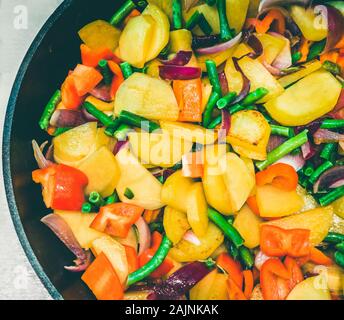 Nahaufnahme von Rühren braten im Wok mit verschiedenen Gemüse wie Kartoffeln, Paprika, Grüne Bohnen, Zwiebeln. Stockfoto