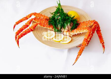 Red king crab auf einem Teller mit Zitrone und Dill. Weißer Hintergrund Stockfoto