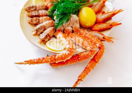 Rote König Krabben und Garnelen auf einem Teller mit Zitrone und Dill. Weißer Hintergrund Stockfoto