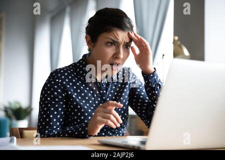 Schockiert junge indische Mädchen Blick auf Laptop Bildschirm fühlen Angst Stockfoto