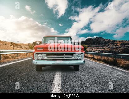 Ein klassisches Automobil auf eine Reise auf das Land raod gegen die trübe und blauer Himmel. Stockfoto
