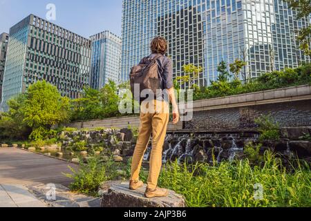 Junger Mann Tourist in Cheonggyecheon Strom in Seoul, Korea. Cheonggyecheon Strom ist das Ergebnis einer massiven Stadterneuerung Projekt. Reisen nach Korea Stockfoto