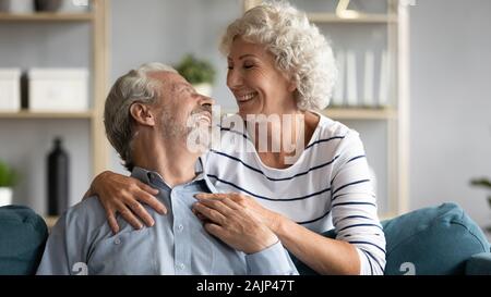 Liebevolle Frau umarmt Geliebten grauhaariger Mann von hinten Stockfoto