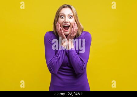 Unglaubliche Neuigkeiten! Portrait von glücklich überrascht Frau mit weit geöffnetem Mund und großen Augen halten die Hände auf das Gesicht, die durch plötzliche grosse Nachrichten schockiert. ind Stockfoto