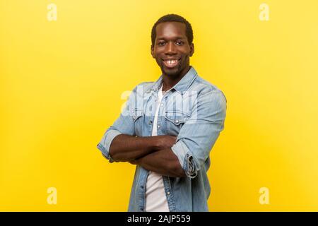 Portrait von positiven erfolgreicher Mensch in casual Shirt mit aufgerollten Ärmeln stehend mit gekreuzten Händen und Kamera mit weißen toothy Lächeln. Stockfoto