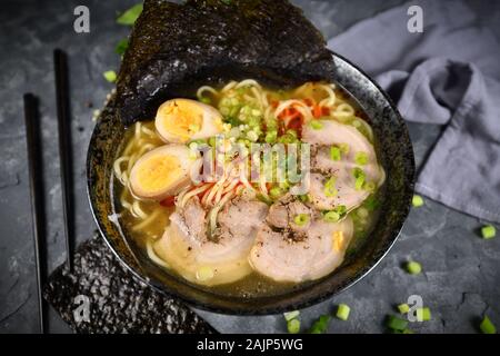 Hausgemachte traditiona japanische Ramen noudle Suppe mit Wurst, Eier und Frühlingszwiebeln in dunklen Schale Stockfoto