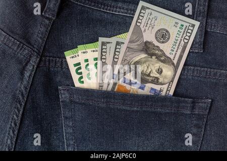 Viele Dollar und Euro aus der Gesäßtasche der Jeans kleben Schuß Nahaufnahme. Stockfoto