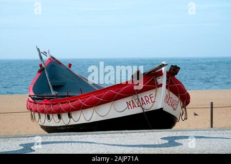 Traditionelle rot, weiß und blau Holz- Portugiesische Fischerboot auf den Strand von Nazare, Portugal. Diese Boote sind auf dem Display durch die trockenen Fisch Museum Stockfoto