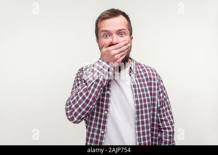 Ich werde nicht erzählen! Portrait von eingeschüchtert, bärtiger Mann im casual Plaid Shirt über den Mund mit der Hand, erschrocken, um zu bezeugen, dass die Pflege von geheimen Informationen. Stockfoto