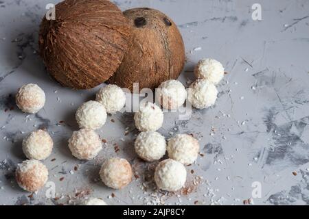 Bonbons in Kokosraspeln und frische Kokosnuss mit Leinsamen auf grauem Stein. Energie Kugeln. Kopieren Sie Platz. Stockfoto