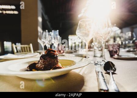 Exquisite Kalbfleisch Gericht mit Soße in Luxus Besteck serviert mit Sonnenstrahlen in einem Restaurant. Stockfoto