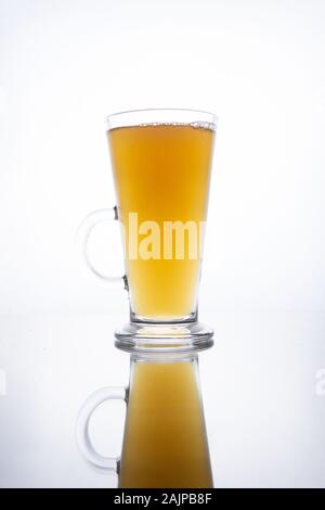 Licht unfiltrierte Bier ergossen sich in eine dampfende Tasse auf einem weißen Hintergrund mit Reflektion Stockfoto