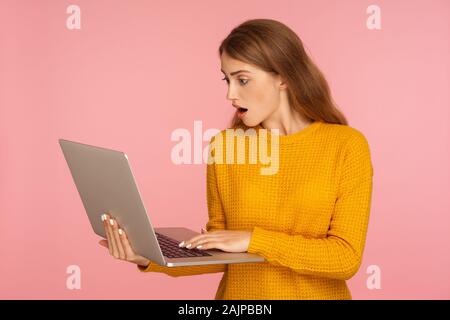 Portrait der erstaunt Ingwer Mädchen Pullover mit Laptop und Arbeiten, die Eingabe über Tastatur und Suchen mit Staunen und Schock, mit Computer. ind Stockfoto