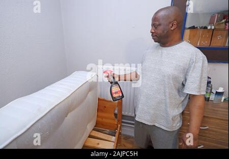 Lesley Mkoko, 51, die swasiland vor drei Jahren flohen, Sprays Matratze Wanzen in seiner direkten Bereitstellung Zimmer zu töten, dass er Aktien mit zwei anderen Männern bei Viking Haus in Waterford. Stockfoto