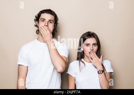 Portrait von attraktiven Paar tragen weiße t-shirt große Nachrichten Freude Reaktion über beige Farbe Hintergrund Stockfoto