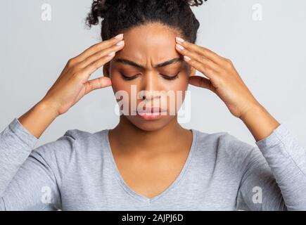 Junge traurig afro Frau mit Kopfschmerzen, ihr Tempel, Migräne Konzept berühren Stockfoto