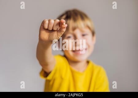 Litle kaukasischen Junge hält einen fallengelassen Milchzahn zwischen seinen Fingern und lacht in die Kamera Stockfoto