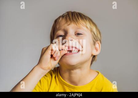 Litle kaukasischen Junge hält einen fallengelassen Milchzahn zwischen seinen Fingern und lacht in die Kamera Stockfoto