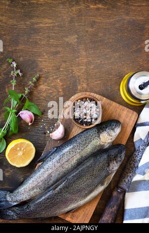 Frische rohe Forelle Fisch und Gurke Zutaten auf einem Holztisch. Kochen Fisch Vorbereitung. Ansicht von oben flach Hintergrund. Kopieren Sie Platz. Stockfoto