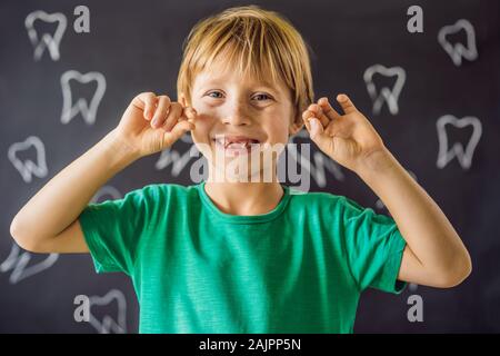 Litle kaukasischen Junge hält einen fallengelassen Milchzahn zwischen seinen Fingern und lacht in die Kamera Stockfoto