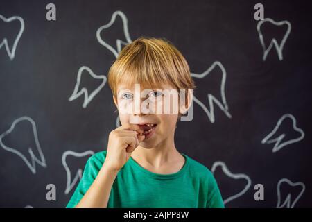 Litle kaukasischen Junge hält einen fallengelassen Milchzahn zwischen seinen Fingern und lacht in die Kamera Stockfoto