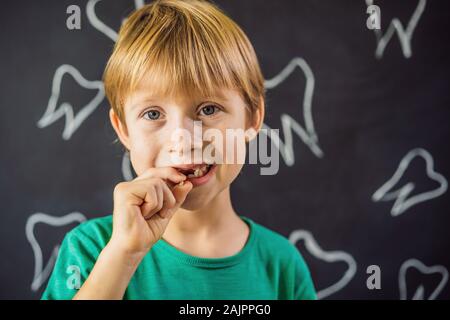 Litle kaukasischen Junge hält einen fallengelassen Milchzahn zwischen seinen Fingern und lacht in die Kamera Stockfoto