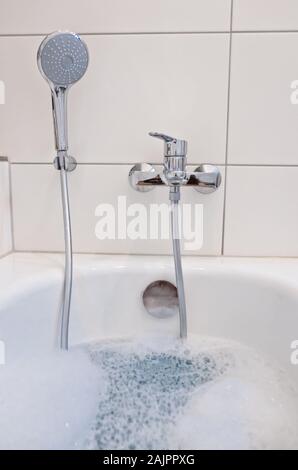 Eine Badewanne im Badezimmer mit warmem Wasser und Schaum gefüllt Stockfoto