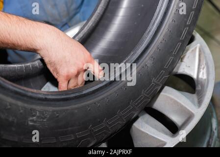 Der Master prüft die Reifen von der Festplatte des Autos entfernt. Austausch der Gummi vor der Saison. Stockfoto