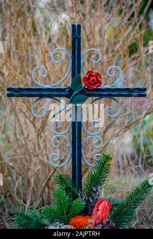 Friedhof Tegel, Berlin, Deutschland - 29 November 2018: Cast Iron Cross mit einer roten Rose auf einem Grab Stockfoto