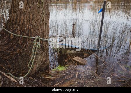 Ein versunkenes Ruderboot liegt am Ufer eines kleinen Sees Stockfoto