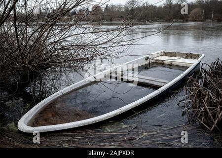 Ein versunkenes Ruderboot liegt am Ufer eines kleinen Sees Stockfoto