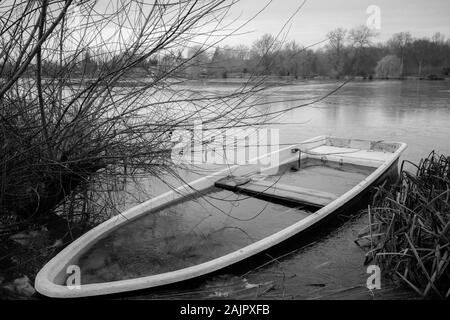 Ein versunkenes Ruderboot liegt am Ufer eines kleinen Sees Stockfoto