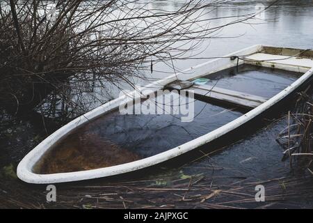 Ein versunkenes Ruderboot liegt am Ufer eines kleinen Sees Stockfoto