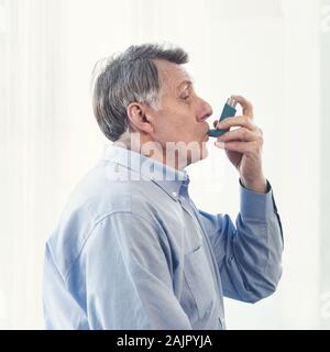 Asthmaanfall. Seitenansicht des reifer Mann mit Inhalator für Allergien in moderne Klinik, kopieren Raum Stockfoto