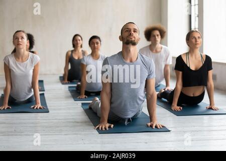 Diverse Leute, die cobra Übung in Gruppe Lektion, Yoga Stockfoto