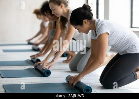 Unterschiedliche Menschen rolling Matten, die Vorbereitung auf die Gruppe Yoga Lektion Stockfoto