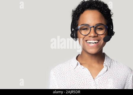 Afrikanische Frau mit Headset mit Mikrofon auf Grau isoliert Posing Stockfoto