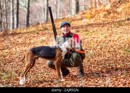 Jäger mit Waffe Jagd und Hund jagen im Wald Stockfoto