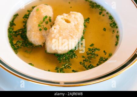 Klare Rinderbrühe mit Butter Knödel, genannt Butternockerl in deutscher Sprache, die Suppe ist ein Teil der traditionellen österreichischen Küche. Stockfoto