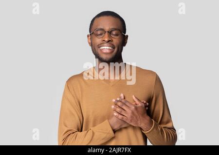 Afrikanische Kerl hält die Hände auf der Brust mit Dankbarkeit studio Shot Stockfoto