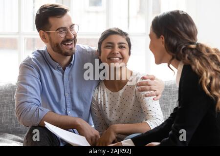 Internationale Paare im Gespräch mit weiblichen Realtor in der Sitzung aufgeregt Stockfoto