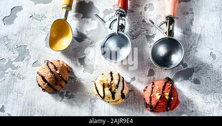 Drei Aromen von cremiges Eis mit Kugeln in einer Reihe auf einem alten grunge Texturierte rustikalen grauer Hintergrund in einer Ansicht von oben angeordnet Stockfoto