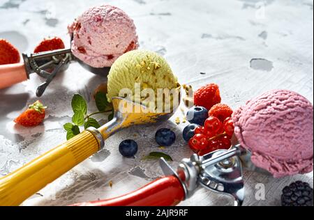 Drei Kugeln mit verschiedenen Aromen von Beeren und Pistazien Eis mit frischen Früchten Zutaten niedrigen Winkel mit Kopie Raum gesehen Stockfoto