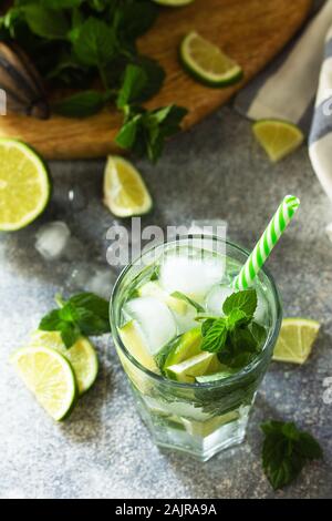Frischen Mojito Cocktail mit Kalk, Eis und Minze im Glas auf einem grauen Stein. Sommer kalte Getränke und Cocktails. Stockfoto