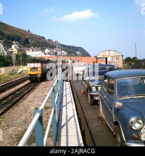 Ende der 1960er Jahre, historische, Autos der Ära mit einem kleinen auf einem autoverlad am Hafen Fishguard, Wales. Autoverlad Betrieben aus London an vielen Orten in Großbritannien und wurde populär, wenn große Entfernungen mit dem Auto Beteiligten erhebliche Fahrzeiten. Der Rail Service 1995, als Britische Bahn privatisiert wurde eingestellt. Stockfoto