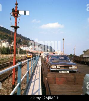 Ende der 1960er Jahre, historische, Autos der ära einschließlich eines Ford Capri auf einem autoverlad am Hafen Fishguard, Wales für Fähren nach Irland. Autoverlad Betrieben aus London an vielen Orten in Großbritannien und war ein beliebter Service, wenn große Entfernungen mit dem Auto Beteiligten erhebliche Fahrzeiten. Der Rail Service 1995, als Britische Bahn privatisiert wurde eingestellt. Stockfoto