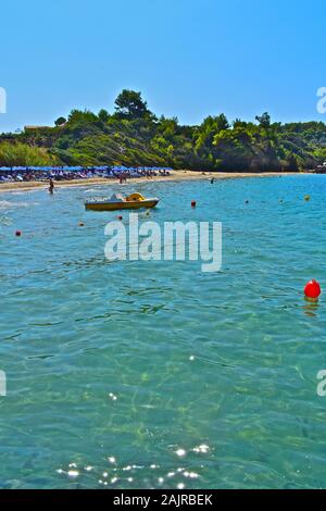 Einen schönen Strand Szene an der Küste in der Nähe von Kefalonia Lassi, in der Nähe der Hauptstadt Argostoli. Reihen von Blue Sun Sonnenschirme. Tretboote günstig an der Küste. Stockfoto