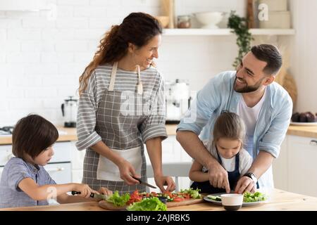 Vollständige Familie mit Kindern plaudern und Vorbereitung gesunde vegetarische Salat Stockfoto