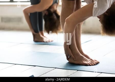 Schließen Sie herauf Leute dehnen in uttanasana darstellen, Yoga Stockfoto